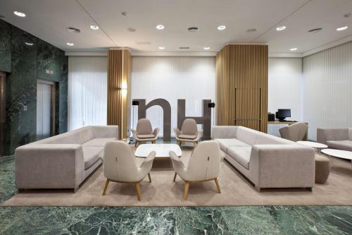 a lobby with couches and a table and chairs at NH Madrid Ventas in Madrid