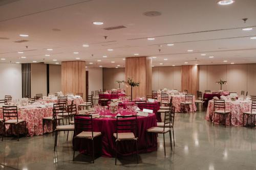 a banquet hall with tables and chairs with red tablecloths at NH Madrid Ventas in Madrid