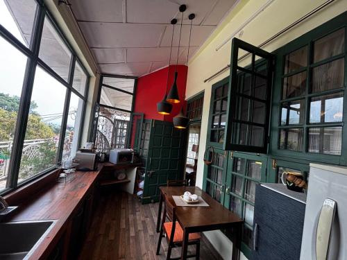 a room with a table and some windows at Frogs BNB Aviator's Bungalow in Dharmsala