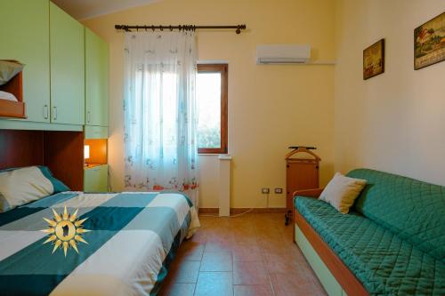 a bedroom with a bed and a couch and a window at Casa dell'Artista - Ampio appartamento in zona tranquilla e centrale in Iglesias