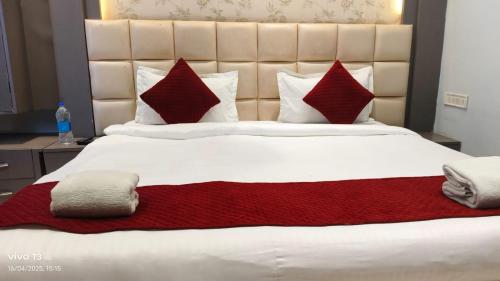 a bedroom with a large bed with red pillows at Hotel Shanti Niketan By Nexottel in Deoghar