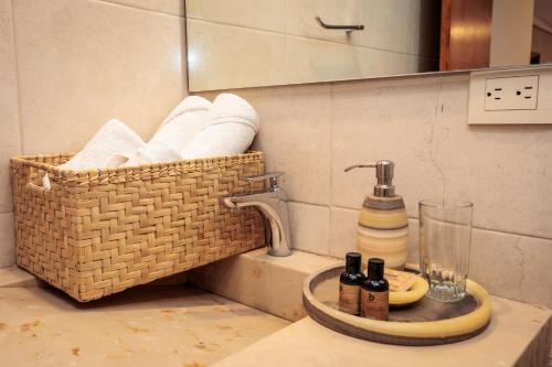 a bathroom sink with a basket of towels at Hotel Rosa Mexicano in Oaxaca City