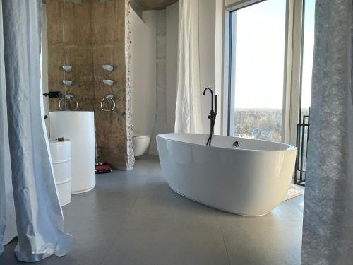 a white bath tub in a bathroom with a window at E64 Wieża Wrocław in Wrocław