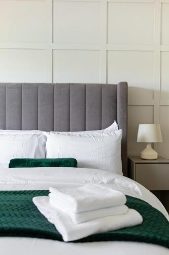 a bed with white pillows and a green blanket at West London Apartment with easy access to Heathrow Airport & Twickenham Rugby Stadium in Hounslow
