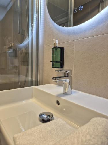 a bathroom sink with a soap dispenser and a mirror at Hotel Den Burg in Den Burg