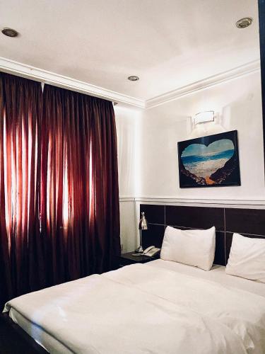 a bedroom with a large bed with red curtains at Starluxury Apartments and Suites in Mama