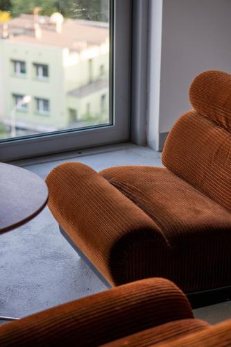 a brown chair in a room with a window at E64 Wieża Wrocław in Wrocław