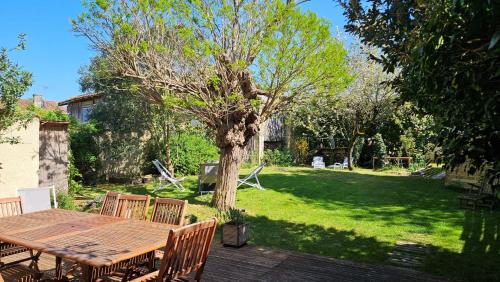 a wooden table and chairs in a yard with a tree at La Maison de la Venise Verte - 4 chambres, jardin in Le Mazeau