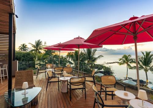 a deck with tables and chairs and red umbrellas at Mystik Life Style by NEWMARK in Mont Choisy