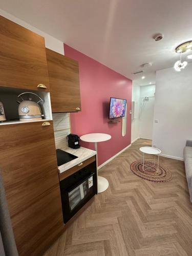 une cuisine avec un mur rose, une table et deux tabourets dans l'établissement MOON - 33, à Nice