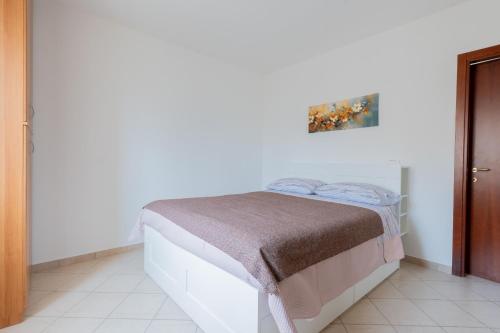 a bed in a white room with a picture on the wall at Luminosa casa a Casoli di Atri con giardino in Atri