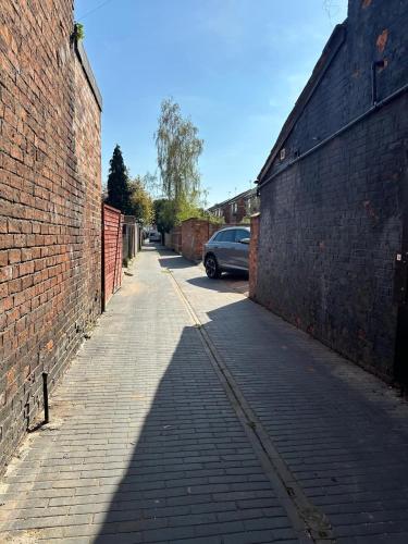 an alley with a car parked next to a brick wall at Bedford Street Flats in Crewe