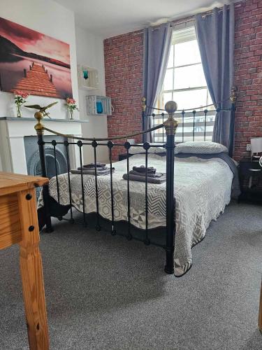 a bedroom with a black bed and a brick wall at Driftwood Apartments Broadstairs in Broadstairs