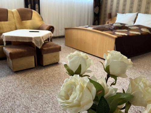 a bedroom with a bed and a chair and flowers at Hotel Leśny in Strzelce Opolskie