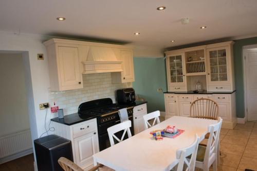 a kitchen with white cabinets and a table with chairs at Mumbles Seaside sleeps up 11 Pets allowed in Swansea
