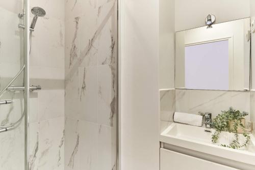 une salle de bain blanche avec une douche et un lavabo dans l'établissement Apartment 2 bedrooms Center of Paris, à Paris