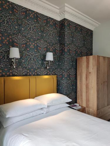 a bedroom with a bed and a wall with floral wallpaper at The Rosedene in Llandudno