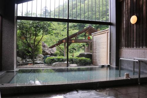 那須鹽原的住宿－大黑屋板室溫泉旅館，透过大窗户可欣赏到花园景色的游泳池
