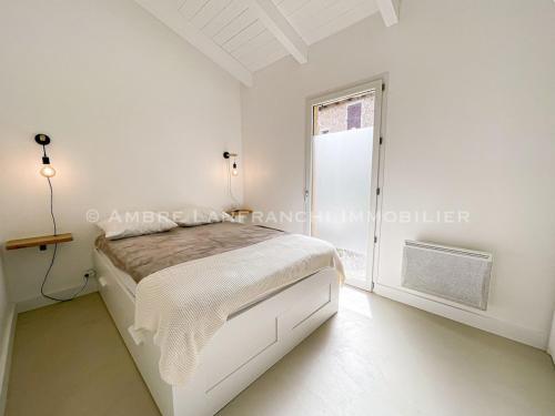 une chambre blanche avec un lit et une fenêtre dans l'établissement Maison en pierre - 6 personnes - piscine, à Porto-Vecchio