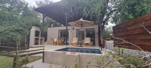 a house with a swimming pool and an umbrella at Buffalo Thorn Villa next to Kruger National Park in Marloth Park
