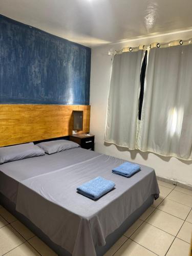 a bedroom with a bed with two blue towels on it at Sonhos ML ApartHotel in Búzios
