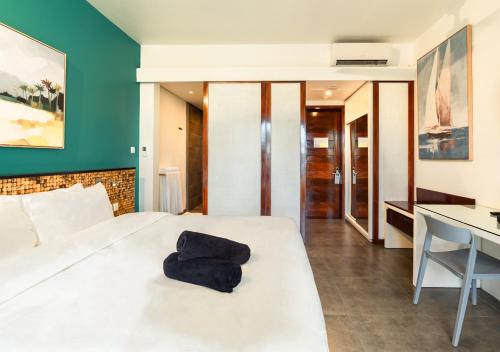 a bedroom with a white bed with a black pillow on it at Mystik Life Style by NEWMARK in Mont Choisy