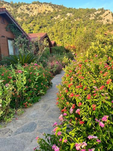 a garden with flowers in front of a house at Leontopolis Apart Otel in Cıralı