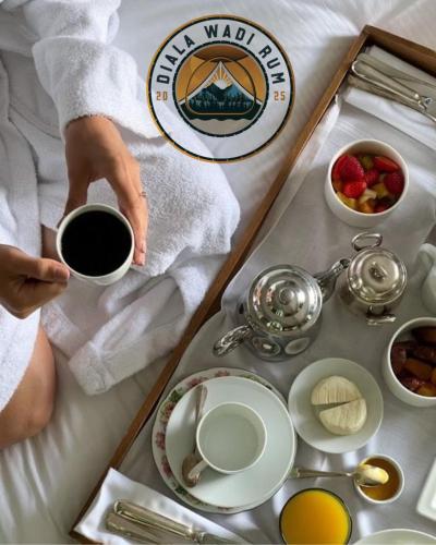 een dienblad met eten met een persoon die een kopje koffie vasthoudt bij Diala luxury wadi rum in Wadi Rum