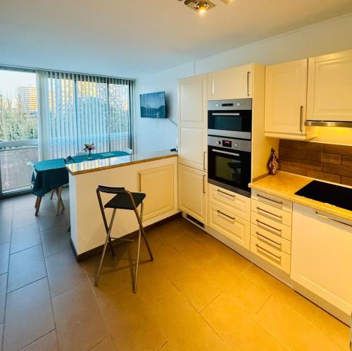 une cuisine avec des armoires blanches et une table et une chaise dans l'établissement Apartement 8 personnes, 4 lits Créteil, metro 20 min de Paris, à Créteil