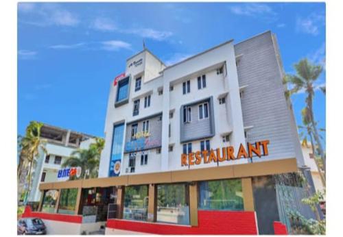 a tall white building with a restaurant sign on it at New ELITTE INN in Trivandrum