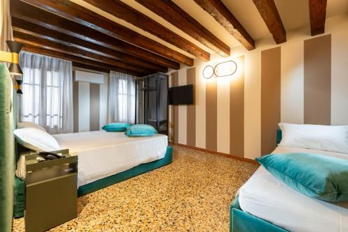 two beds in a room with striped walls at Ca' San Geremia in Venice