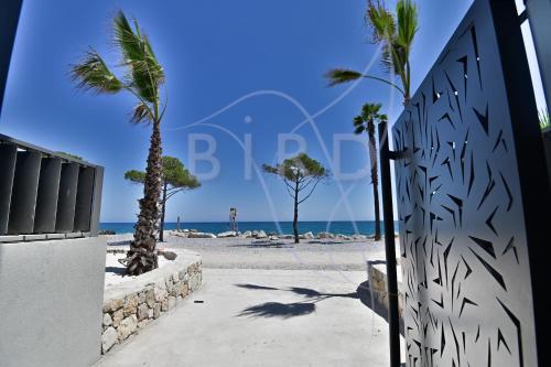 une clôture sur la plage avec des palmiers et l'océan dans l'établissement Waterfront apartment with private garden, à Villeneuve-Loubet
