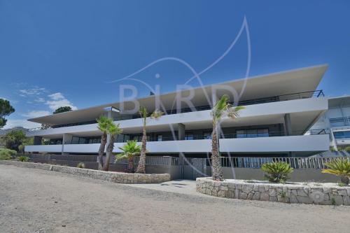 un bâtiment avec des palmiers devant dans l'établissement Waterfront apartment with private garden, à Villeneuve-Loubet