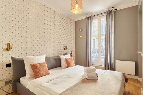 - une chambre avec un grand lit blanc devant une fenêtre dans l'établissement Apartment Opéra by Studio prestige, à Paris