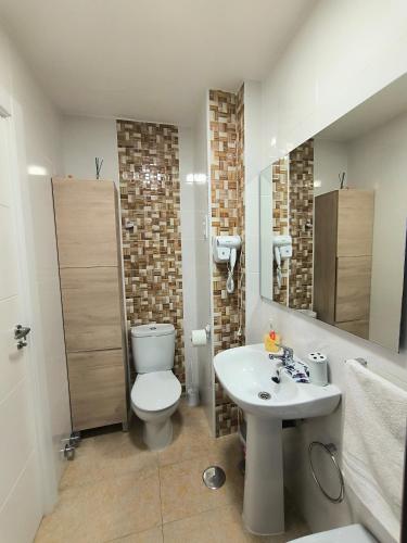 a bathroom with a white toilet and a sink at Alojamiento La Paz in Linares