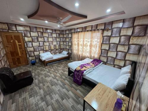 a bedroom with two beds in a room with a wall at Valhalla Guest House Skardu in Skardu