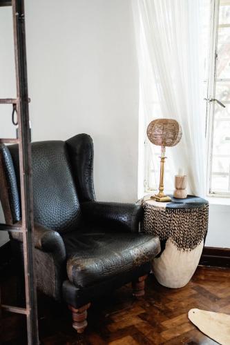 a black leather chair and a lamp on a table at 31 Kisinja, Jinja in Jinja