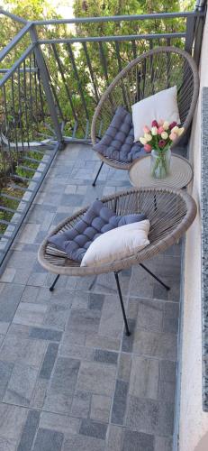 eine Terrasse mit 2 Stühlen und einem Tisch mit einer Blumenvase in der Unterkunft Apartments Jamice in Novi Vinodolski