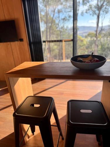 a bowl of fruit sitting on a wooden table with two stools at Richmond Wildlife Haven in Richmond