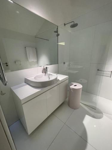 a white bathroom with a sink and a shower at Luxury Penthouse with 2 Pools in a Monastery in Tavira