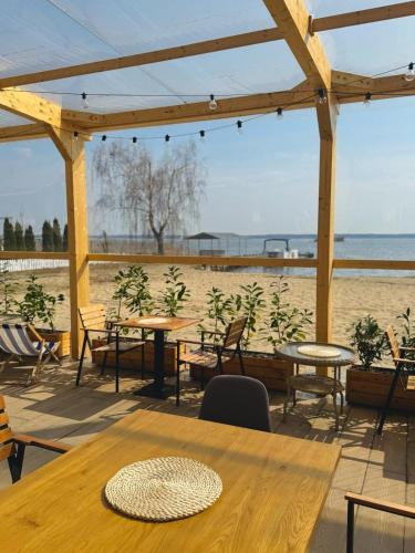 a patio with tables and chairs and a beach at Relax place & restaurant in Zegrze Południowe