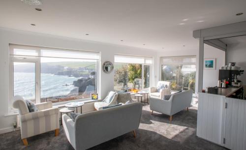 a living room with white furniture and a view of the ocean at Mevagissey Bay Hotel in Mevagissey