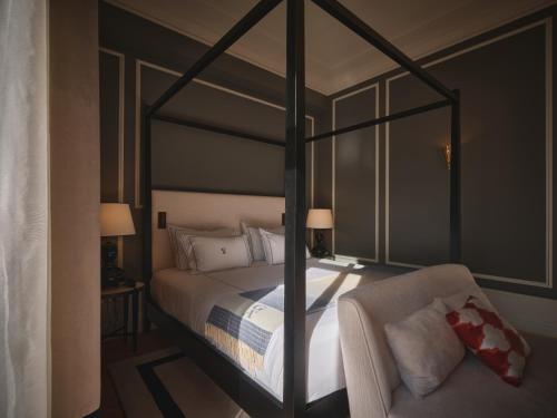 a bedroom with a canopy bed and a chair at GA Palace Hotel & Spa, a XIXth-Century Villa in Porto