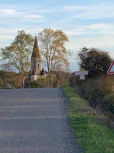 une route menant à une église avec un panneau indiquant la rue dans l'établissement La maisonnette, à Le Nayrac