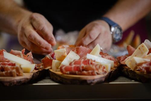 a person preparing food on a table with cheese and meat at Agriturismo San Carlo in Pomarance