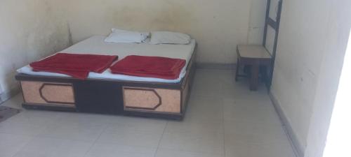 a small room with a bed with two red sheets at Hotel Sangam sagar in Sāgar