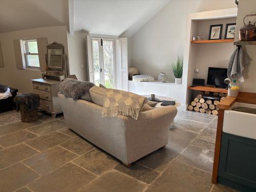 a living room with a couch sitting on a tile floor at Street Farmhouse in Godshill