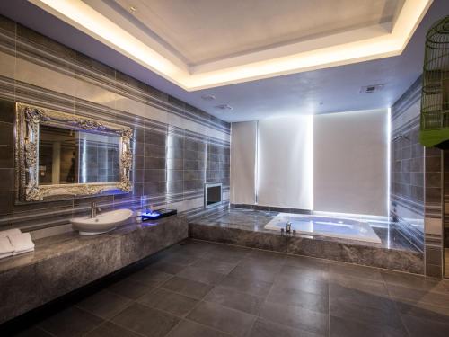 a bathroom with a tub and a sink and a mirror at U-Her Hotel in Taichung