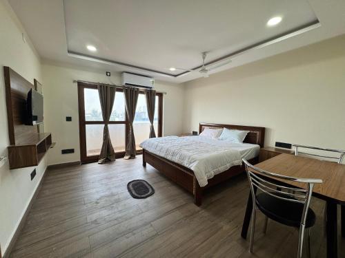 ein Schlafzimmer mit einem Bett und einem Tisch und einem Fernseher in der Unterkunft HOTEL MADHAVA RESiDENCY in Kakinada