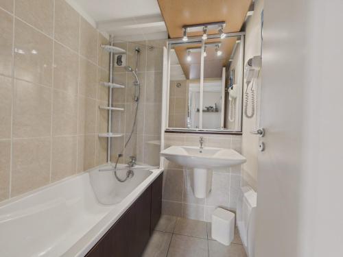 Un baño con bañera, lavabo y bañera. en Balcon vue mer accès direct plage et piscine, en Le Croisic